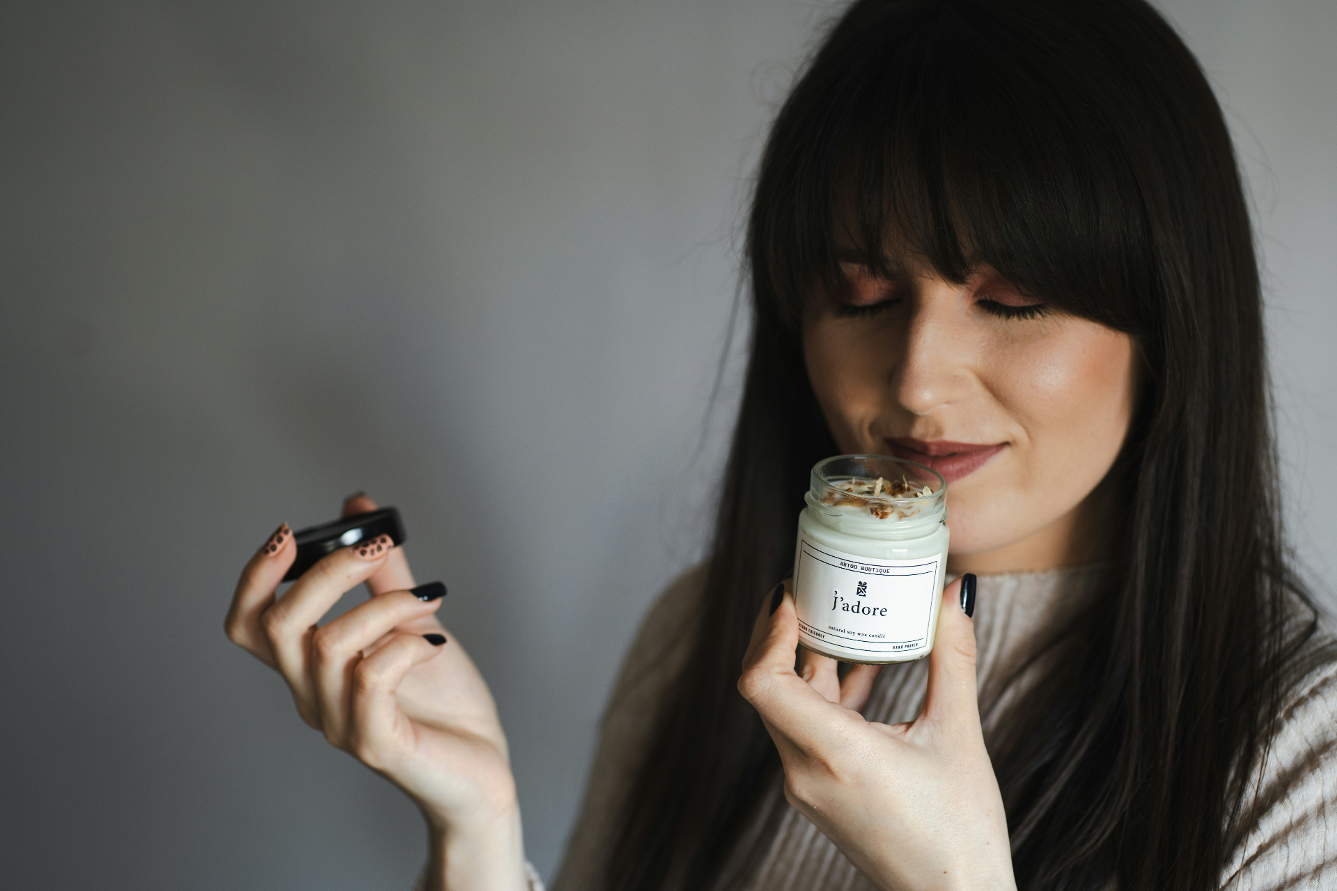 Woman smelling a hand-poured soy candle in a glass jar