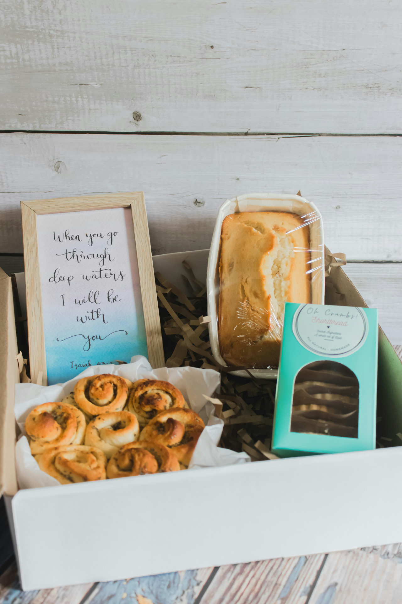 Honey jar, coffee bag, and wrapped artisan treats on linen with dried wildflowers